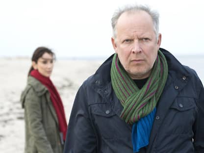 Tatort Kiel Borowski guckt ernst im Hintergrund Wasser und seine Kollegin