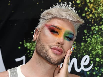 David Lovric mit Regenbogen Make-up und hand an der Wange.