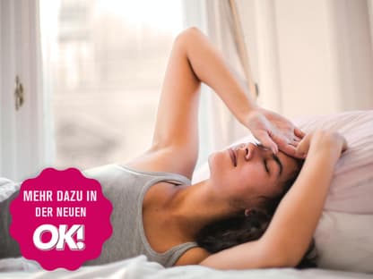 Frau liegt mit Kopfschmerzen im Bett