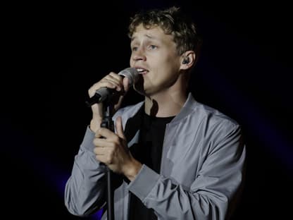 Tim Bendzko guckt traurig beim singen mit einer Hand am Mikro