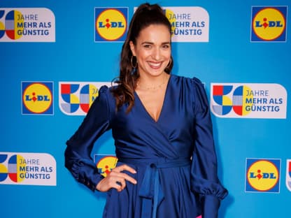 Sally Özcan lächelt im blauen Kleid