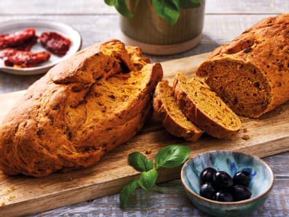 Tomaten-Ciabatta-Brot mit Kräutern auf einem Holzbrett