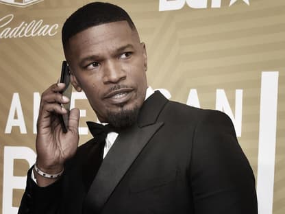 Jamie Foxx hält sich ein Handy ans Ohr und sieht ernst zur Seite