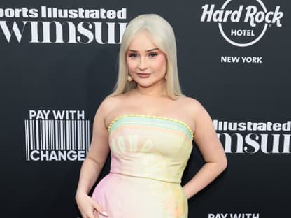 Kim Petras posiert vor einer dunklen Wand