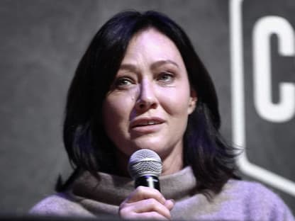 Shannen Doherty hält Mikrofon in der Hand und sieht traurig aus