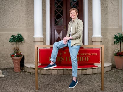 Sturm der Liebe Lukas Leibe sitzt auf Fürstenhof-Schild