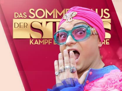 Julian F. M. Stoeckel guckt überrascht mit Hand vor dem Mund vor dem Logo von "Das Sommerhaus der Stars"