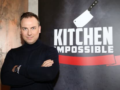 Tim Raue vor einer "Kitchen Impossible"-Wand