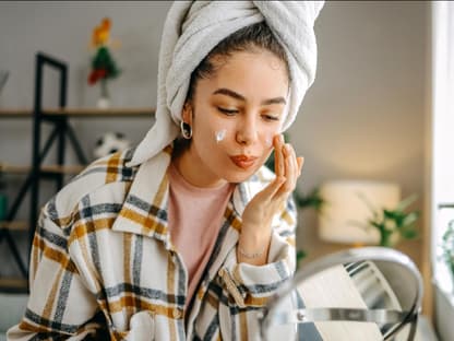 Frau verwendet Anti-Aging-Creme vor Kosmetikspiegel