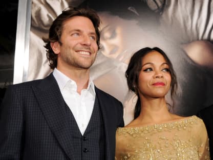 Bradley Cooper im Anzug und  Zoe Saldaña im goldenen Kleid stehen nebeneinander