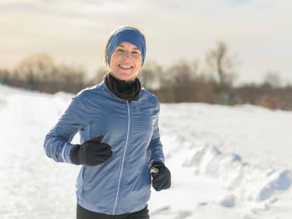 Frau joggt lächelnd im Schnee