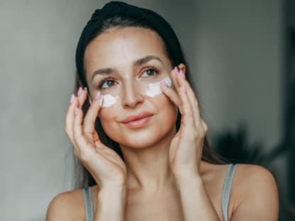 Frau mit Anti-Aging-Creme auf Wange