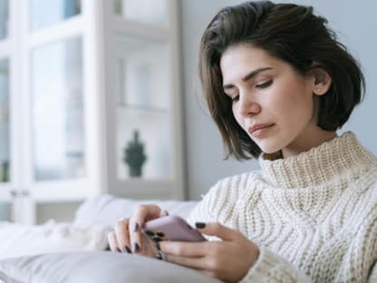 Frau schaut traurig auf ihr Smartphone