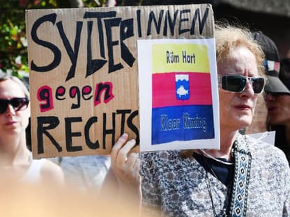 Frau demonstriert nach Rassismus-Skandal auf Sylt mit Plakat