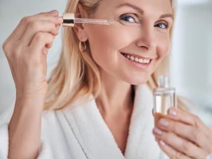 Frau Ü50 trägt Anti-Aging-Serum auf