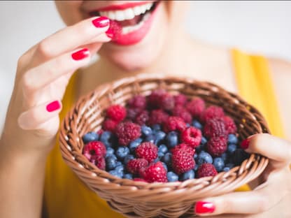 Frau isst Blau- und Himbeeren