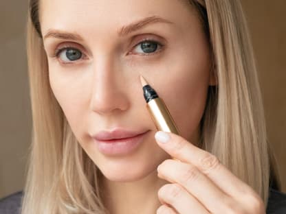 Frau trägt Concealer unter Augen auf