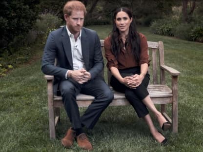 Prinz Harry und Herzogin Meghan sitzen gemeinsam auf einer Bank, schauen ernst