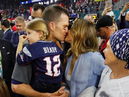 Tom Brady küsst Gisele Bündchen, er hat ihre gemeinsame Tochter auf dem Arm