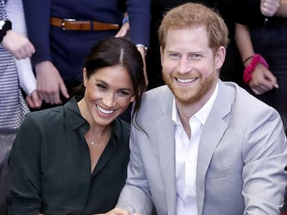 Herzogin Meghan lehnt sich lachend an Prinz Harry