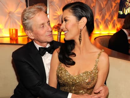 Michael Douglas und Catherine Zeta-Jones lächeln sich an und liegen sich in den Armen