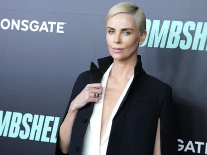 Charlize Theron hält den Kragen ihrer Jacke fest