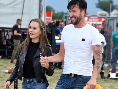 Laura Müller und Michael Wendler laufen Hand in Hand über eine Wiese und grinsen