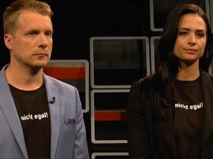 Oliver Pocher und Amira Pocher stehen mit Abstand zu einander und gucken streng.