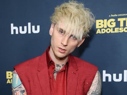 Machine Gun Kelly guckt in die Kamera, roter Anzug