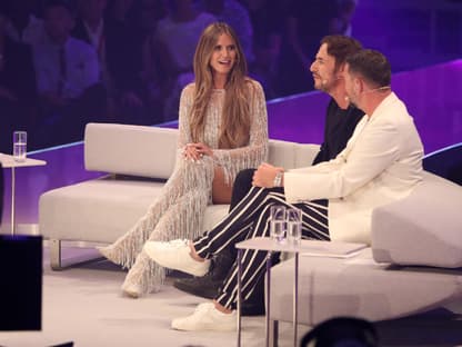 Heidi Klum, Thomas Hayo und Thomas Rath sitzen im GNTM-Finale auf einem weißen Sofa. 