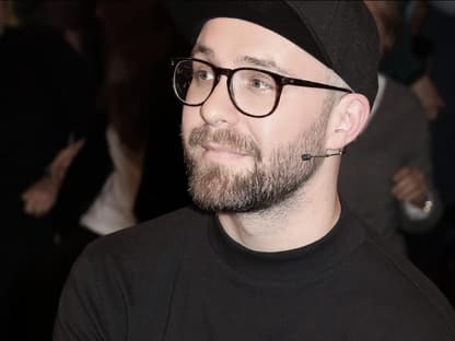 Mark Forster guckt ernst zur Seite mit Brille und Cappy auf