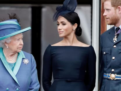 Die Queen, Meghan und Harry stehen nebeneinander und gucken ernst