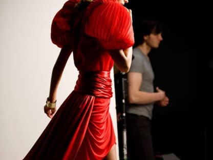 Julia Stegner lächelt in einem roten Seidenkleid von Anne Valérie Hash.