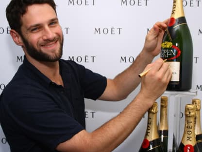 Schauspieler Justin Bartha signiert eine Flasche