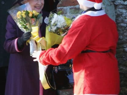 Queen Elisabeth II bekommt von einem verkleideten Santa Claus Blumen überreicht