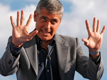 George Clooney spricht zu den Zuschauern, er verspricht Hilfe und möchte in der zerstörten Stadt einen Kinofilm drehen