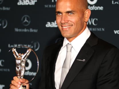 Surfer Kelly Slater hält stolz seine Trophäe in der Hand