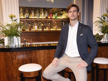 Sandro Kirtzel sitzt auf einem Hocker an einer Bar und guckt ernst