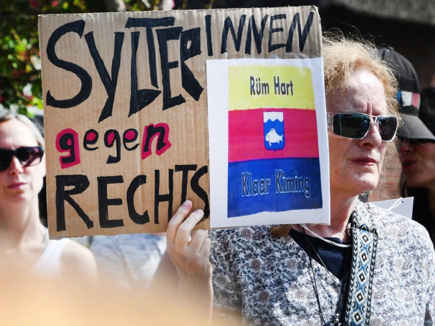 Frau demonstriert nach Rassismus-Skandal auf Sylt mit Plakat